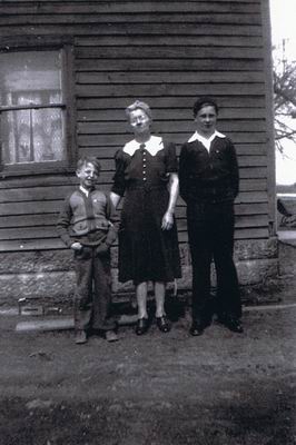 Three people standing outside of home.